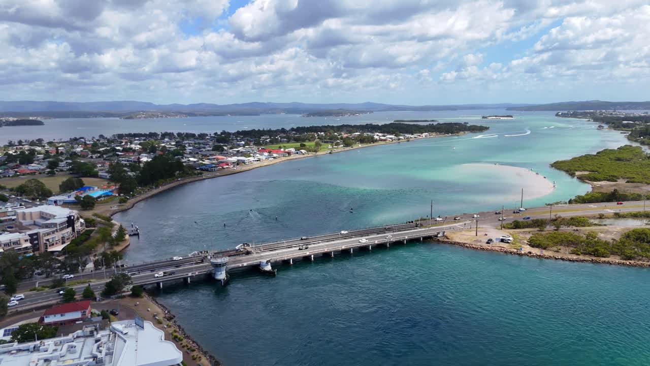 Aerial medium establish of Swansea Bridge crossing lake entrance with boats and town