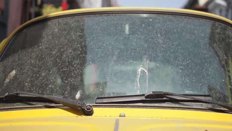 el parabrisas sucio de un coche clásico amarillo