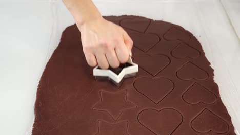 el panadero corta formas de estrellas de la masa de chocolate crudo en la mesa