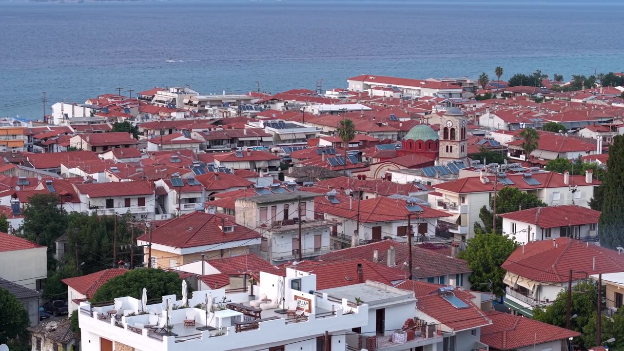 Centro storico del villaggio di Pefkohori con case tradizionali e tetti in terracotta, installazione di pannelli solari, che si affacciano sul Mar Egeo al tramonto, Calcidica. Ripresa con drone.
