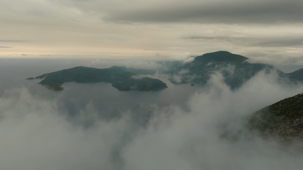 Misty drone view of Ithaca Island Greece showing forested hills and cloudy skies from above