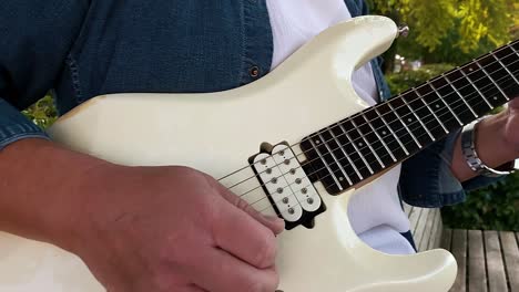 a guitarist playing a guitar in the park sitting on a bench