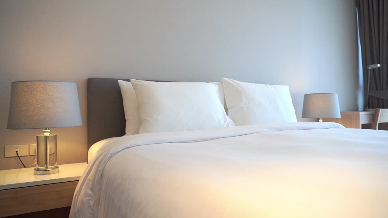 panorámica de izquierda a derecha a través de la cama de una suite de hotel hasta las ventanas.