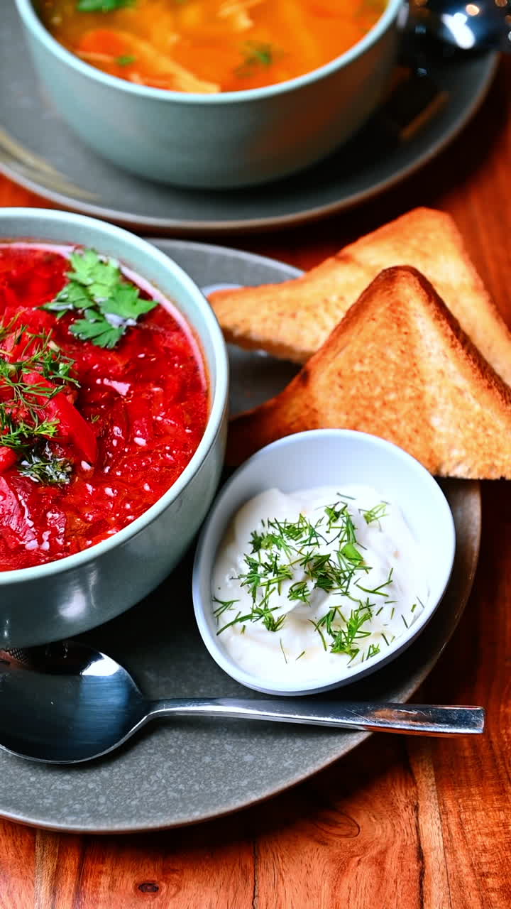 Yeşilliklerle parlak kırmızı çorba. Bir kasede sunulan, yanında kaşığı olan, otlarla canlı kırmızı çorba.
