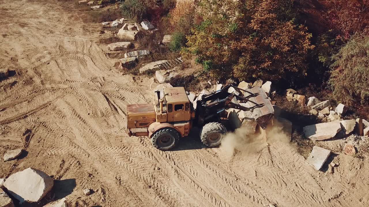 professional bulldozer with a bucket is spreading sand near the stones on the background of the quarry. Close-up