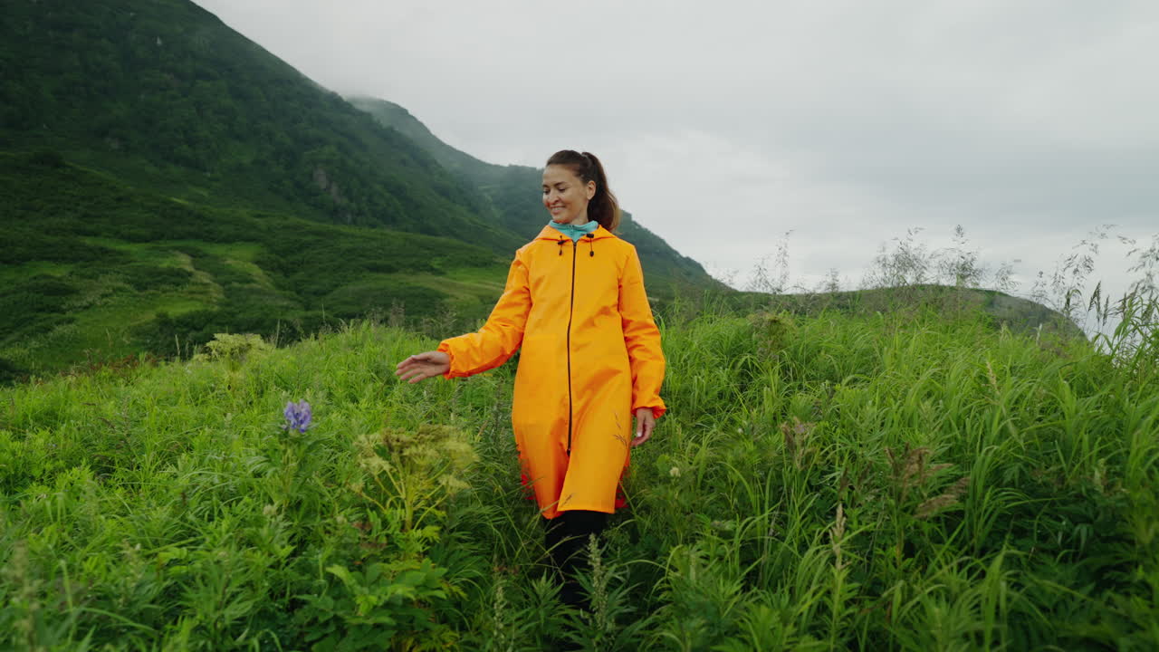 Woman Hiking in Mountains Wearing Orange Raincoat