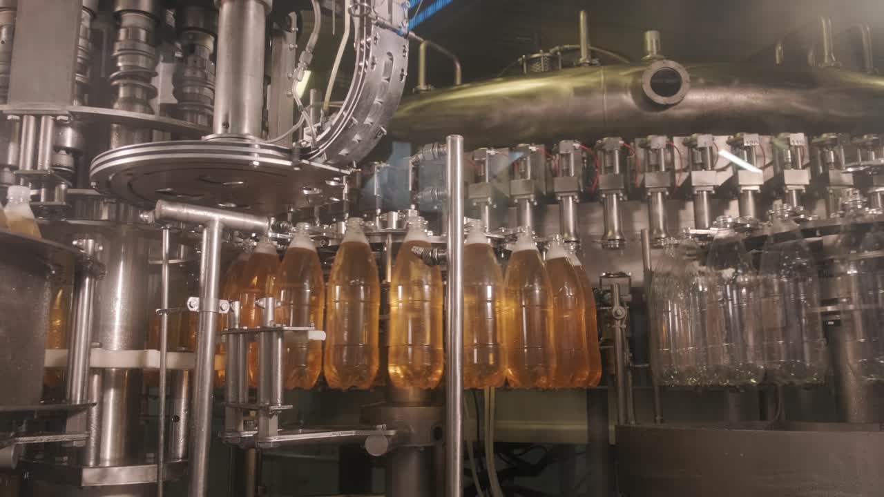 Máquina de envase automática despeja água em garrafas PET de plástico em uma moderna fábrica de bebidas.