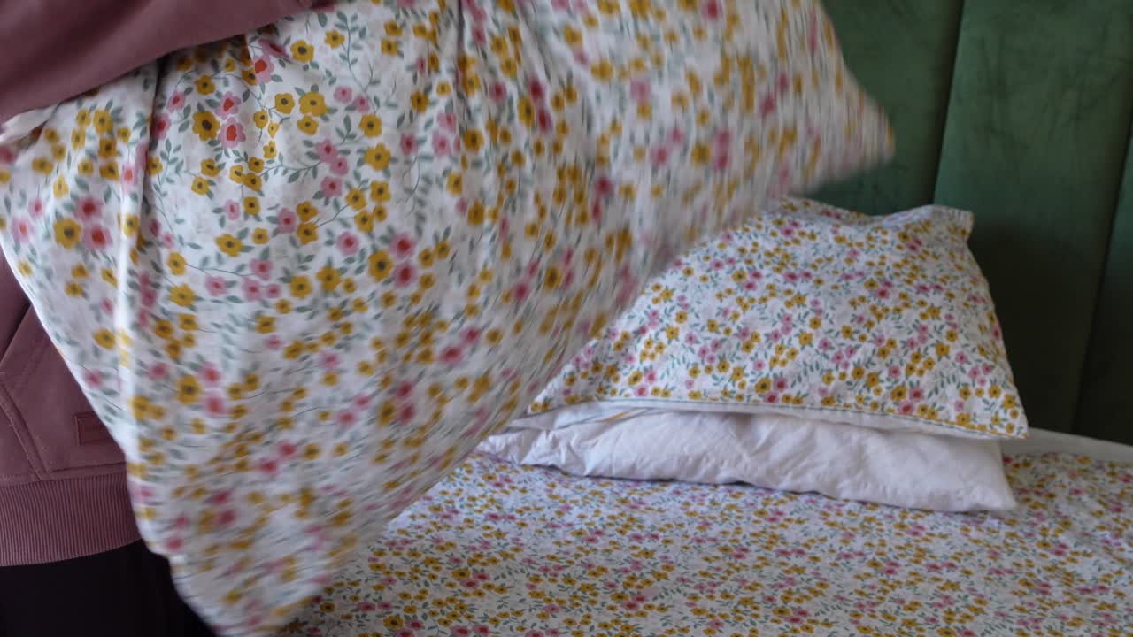 женщина делает постель с цветочной постелью