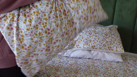 mujer haciendo la cama con ropa de cama floral