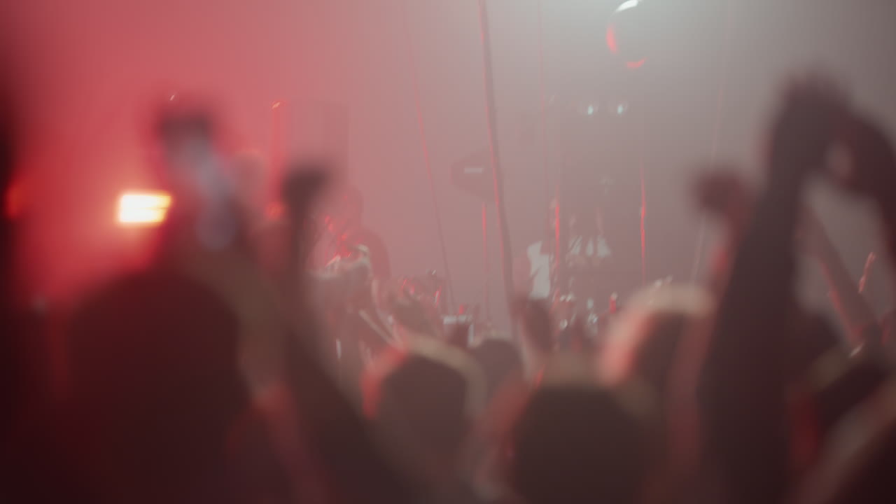 Kerumunan yang Energik di Konser Langsung dengan Lampu Merah yang Remang-remang