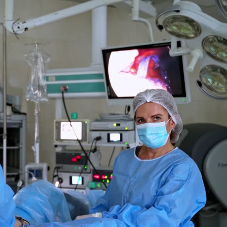 team of doctors during surgery. monitor shows patient's organs at the operating process in hospital. health specialists in medical uniform and mask conduct an operation.