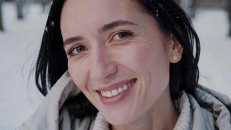 snowflakes gently falling on a smiling woman's hair, enjoying a tranquil moment in a picturesque winter landscape, embracing the serene beauty of the season's chill