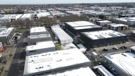 flying over snow covered rooftops with photovoltaic solar panels in an industrial site in winter