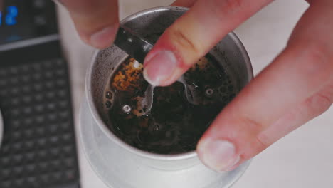 un primer plano de la mano del barista presionando hábilmente un filo de café de metal vietnamita con precisión