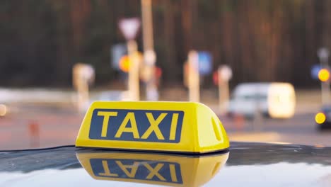 close up of taxi cab sign on a car roof. daytime traffic on the background.