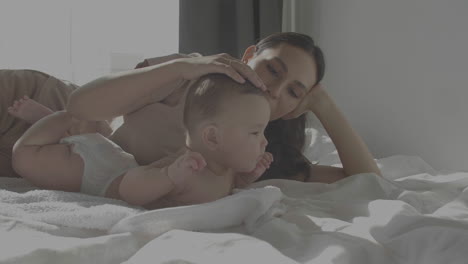 cute happy baby and mom laying in bed