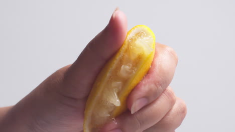 hand squeezes lemon juice on a white background, isolated