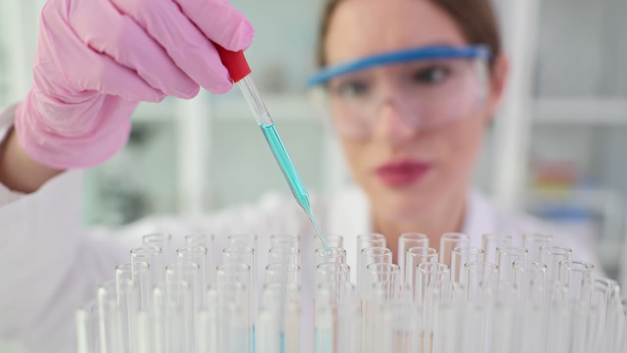 A scientist working with test tubes and a dropper in a lab