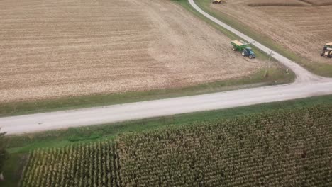 drone flyover view of a green cornfield towards a harvested cornfield