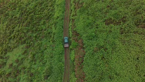 Vista-De-Arriba-Hacia-Abajo-De-Una-Camioneta-Verde-4x4-En-Un-Camino-De-Tierra-En-La-Isla-De-Azores---Disparo-De-Un-Dron