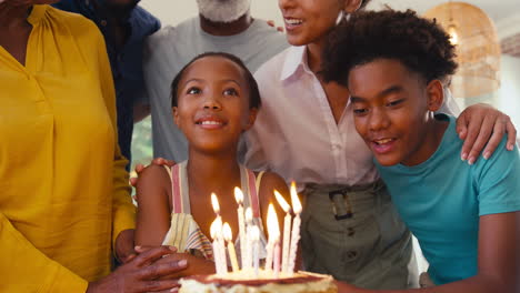 Multi-Generation-Family-Celebrating-Granddaughter's-Birthday-With-Cake-And-Candles-At-Home