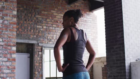 african american woman standing and resting after exercise in an empty urban building