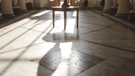 large antique vase on table in spacious pillar hall against sunlight