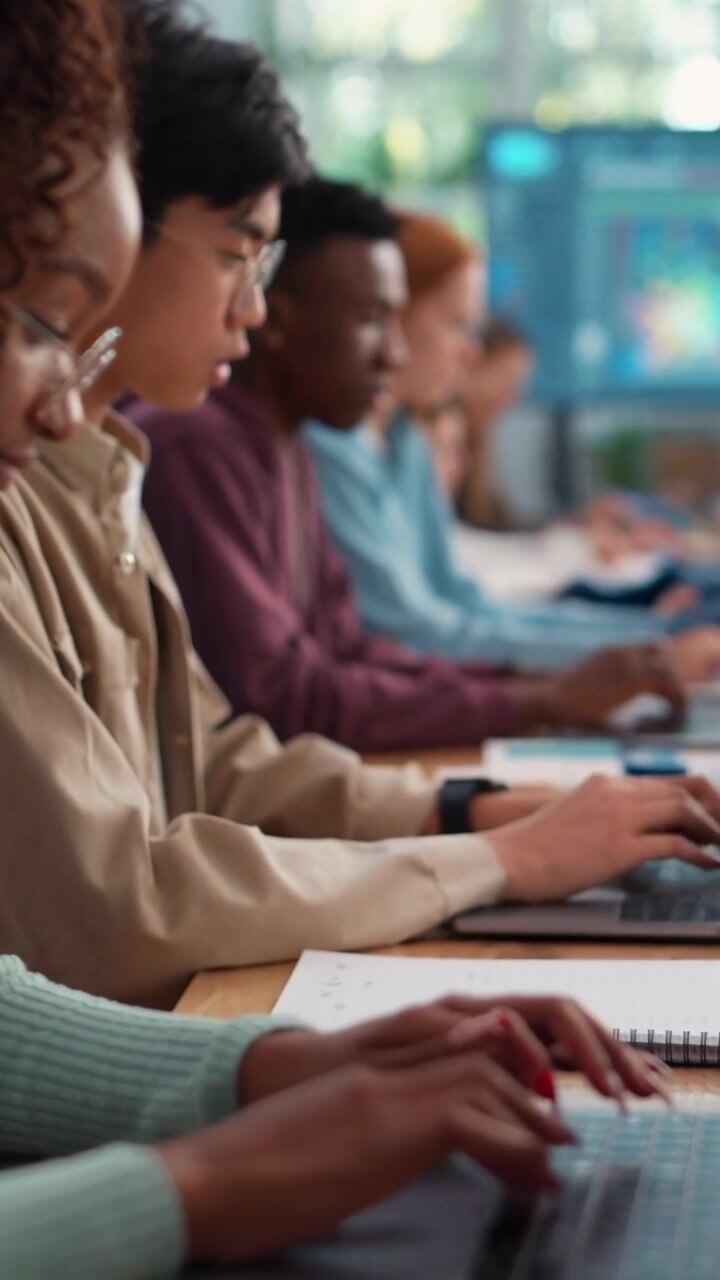 Gruppo Eterogeneo di Studenti che Lavorano sui Laptop in un'Aula Moderna