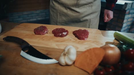 a chef prepares steak cuts on a wooden board with ingredients like garlic and tomatoes