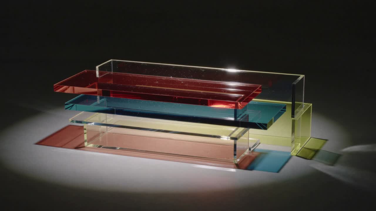Shifting offframe spot bathing acrylic stack on table, revealing yellow support and colored shadows