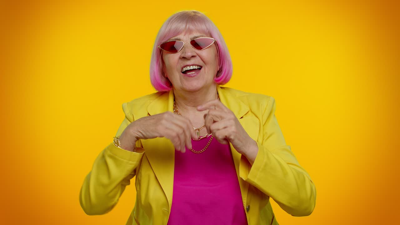 Anziana nonna con gli occhiali da sole ascolta musica, sorride e balla a ritmo, divertendosi.