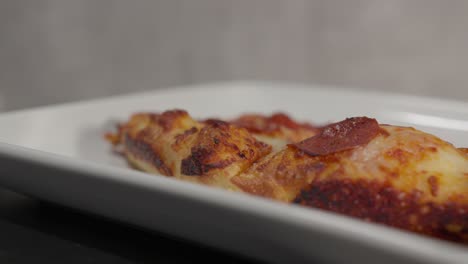 a rotating plate of pizza slices sits indoors, with the bubbling cheese and crispy crust creating an appetizing display