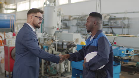 businessman shaking hands with factory worker