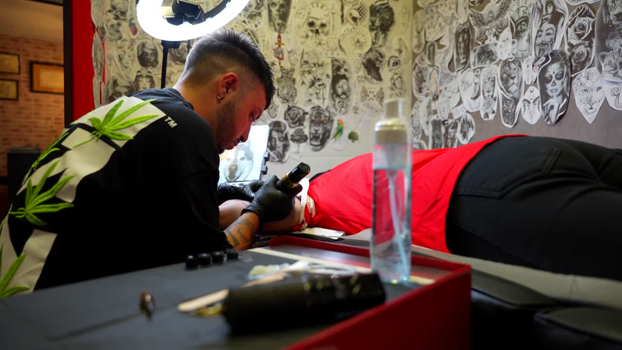 Tatuatore al lavoro in uno studio con luce intensa e diversi strumenti su un tavolo in primo piano