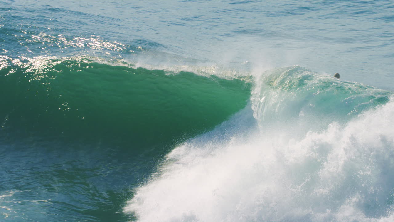 Slow motion view of surfer engulfed by foam ball as they drop into huge wave
