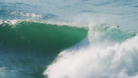 slow motion view of surfer engulfed by foam ball as they drop into huge wave