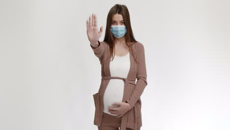 pregnant woman wearing mask gesturing stop