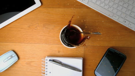 cucharadita con azúcar cayendo en una taza de café y salpicando un escritorio con una tableta pc