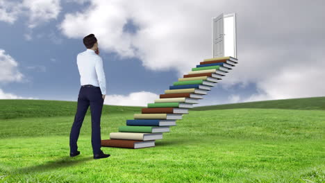 hombre de negocios mirando escaleras hechas de libros en un campo verde