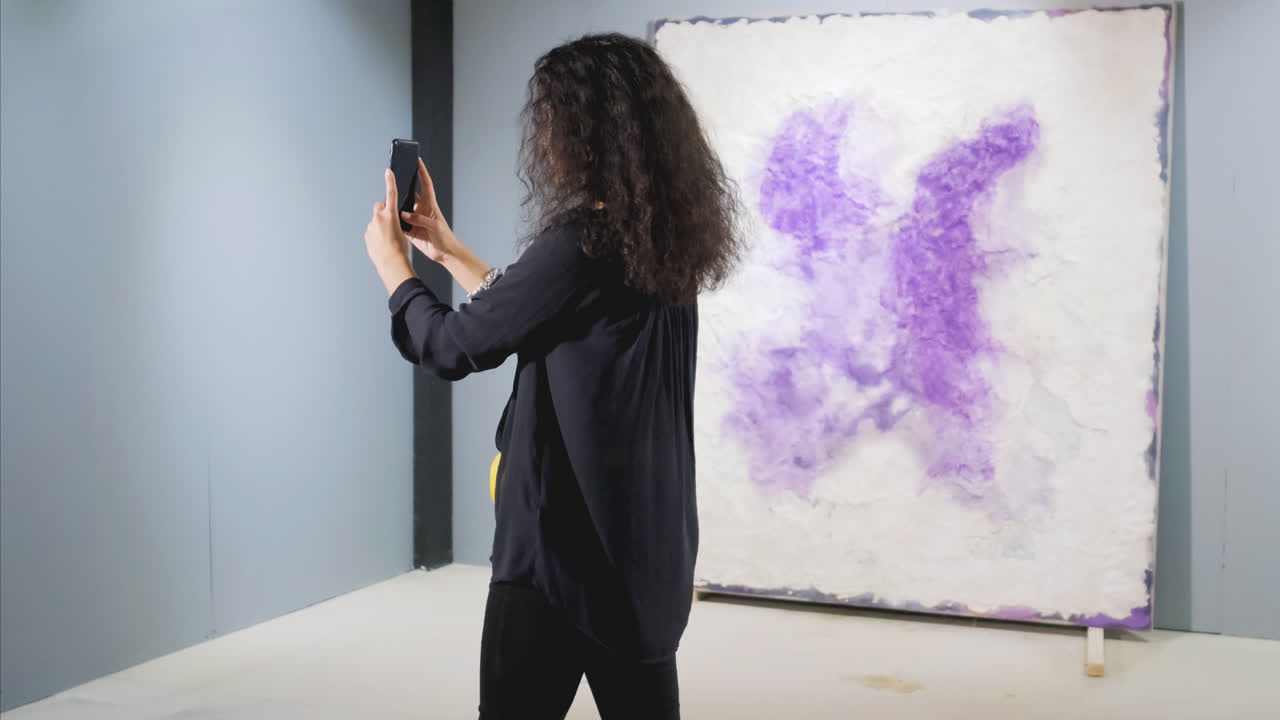 예술 갤러리에서 추상적인 그림의 사진을 찍는 여자