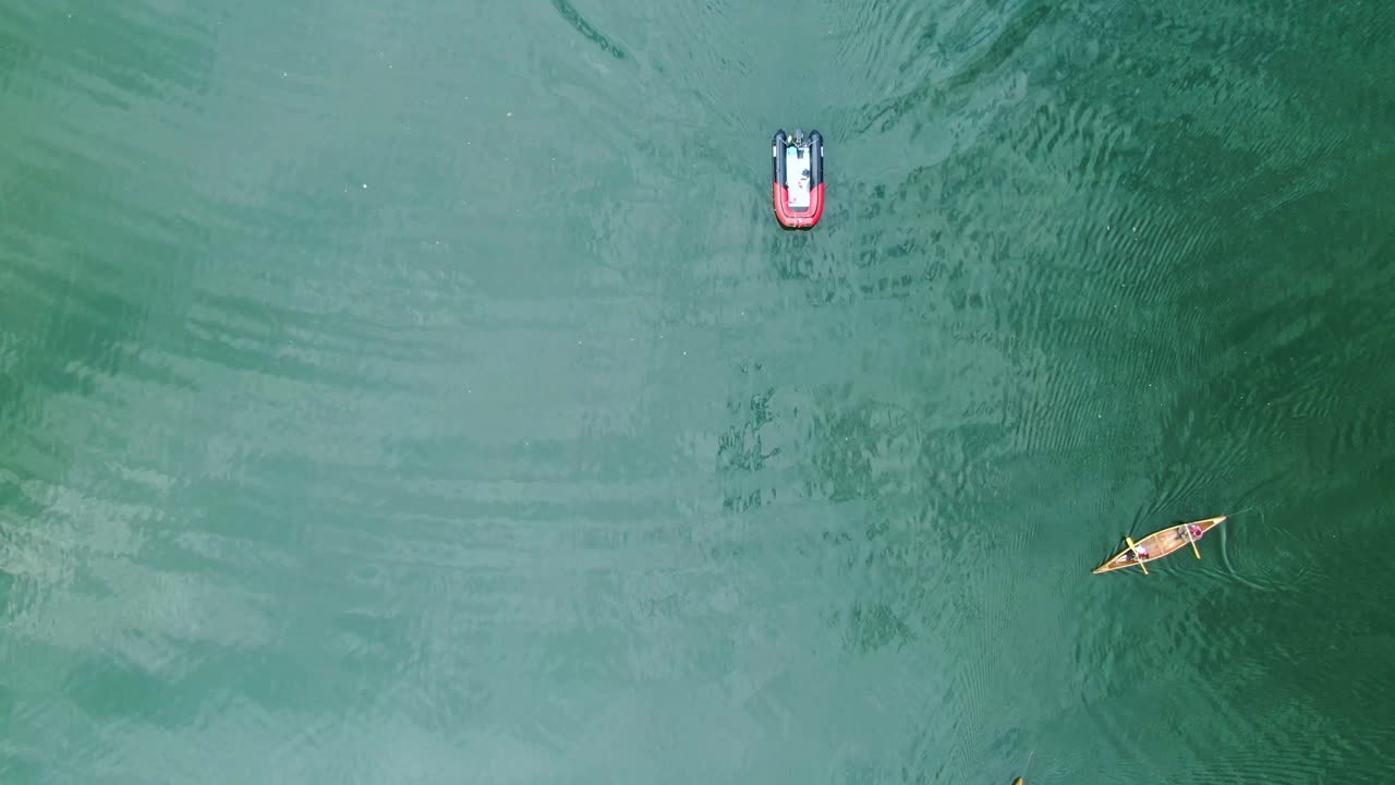 a red motorboat leading the canoe