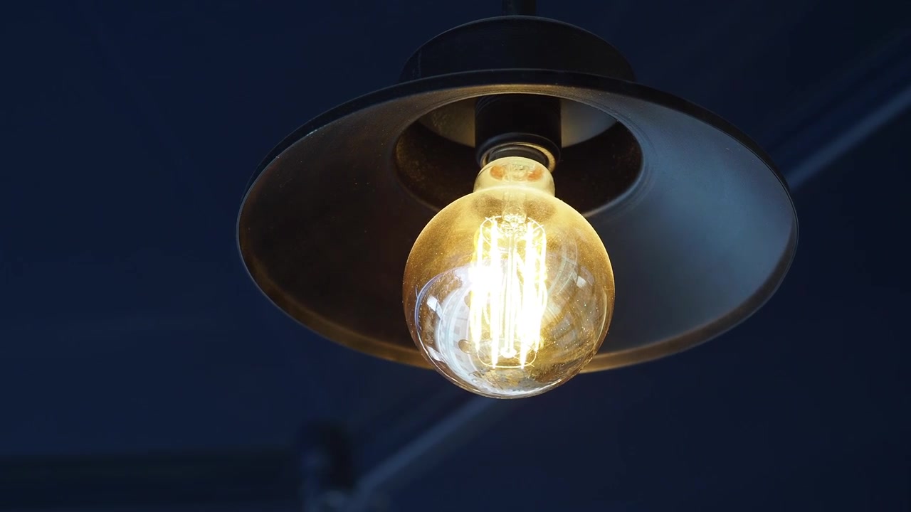 Primo piano di una lampadina Edison incandescente appesa a un portalampada da soffitto