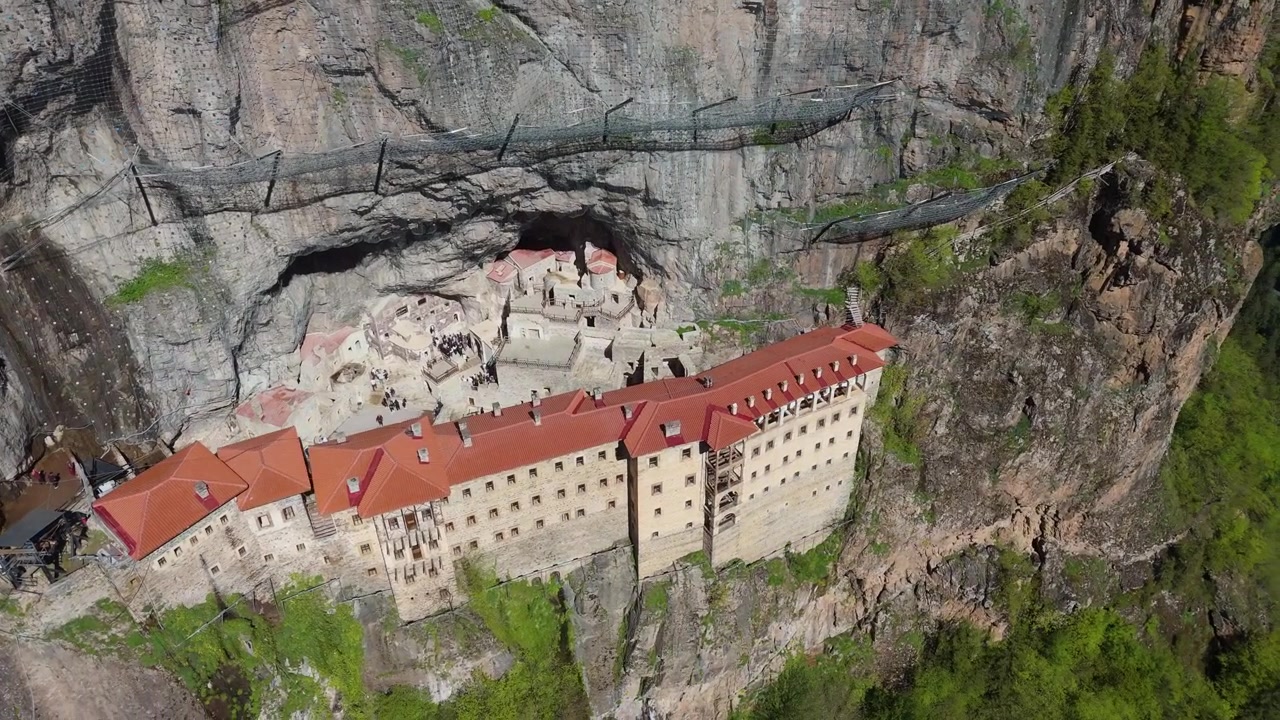 Sumela Monastery nestled among dense green pine woods in Trabzon, Turkey travel destination drone aerial footage