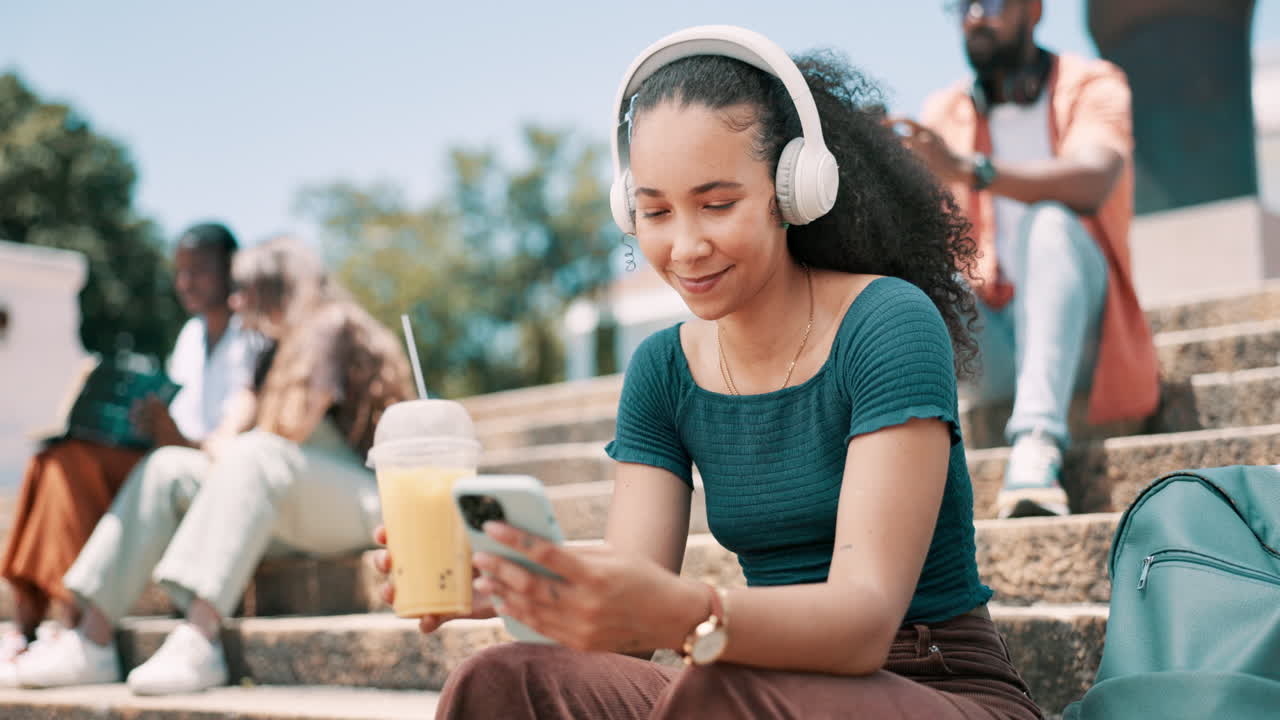 Studentessa che si gusta un frullato e usa il telefono nel campus