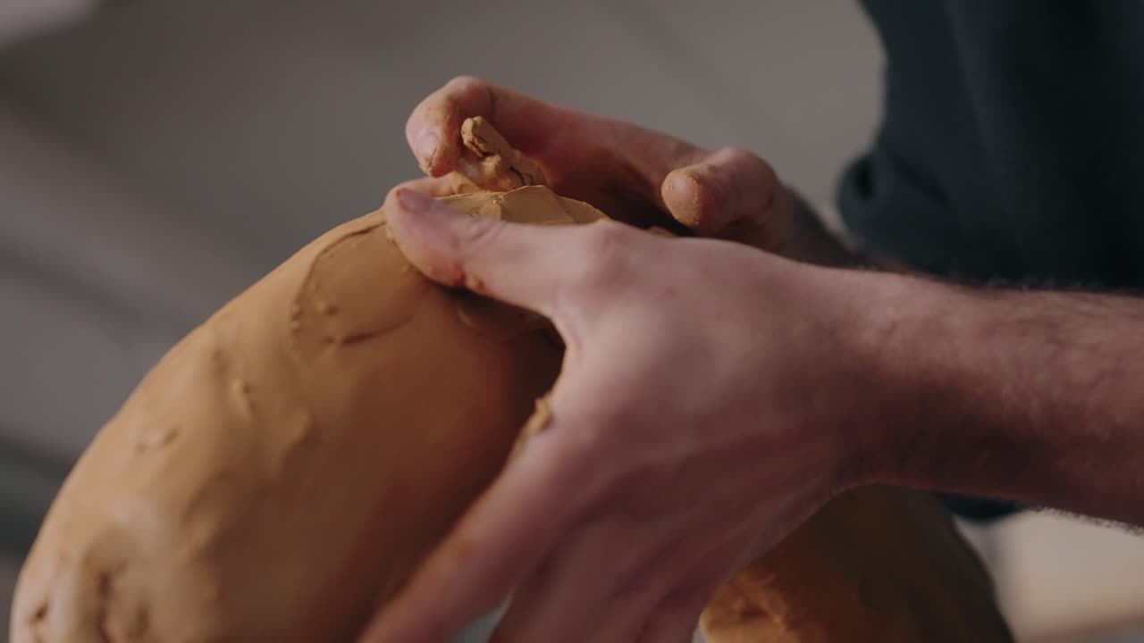 Close up of sculptor modeling clay arch with hands in natural light
