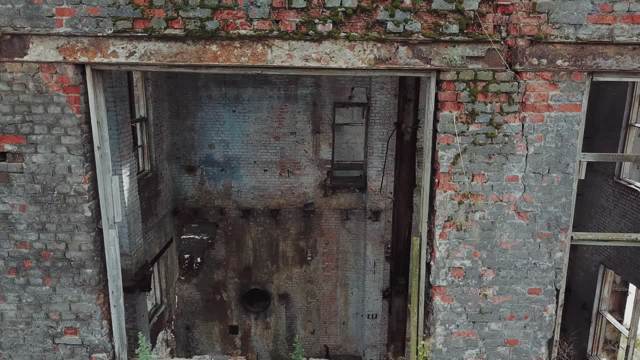 Flight over the destroyed factory. Facade of old industrial building for demolition, broken glass and destroyed frames.