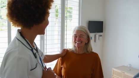 Enfermera-Vestida-De-Uniforme-Reuniéndose-Con-Una-Paciente-Mayor-En-Una-Habitación-De-Hospital-Privada