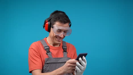 man in safety gear looks amused while using his smartphone