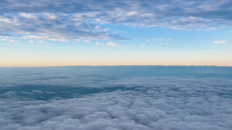 High angle aerial shot of dense stratocumulus clouds during a soft blue and orange sunset