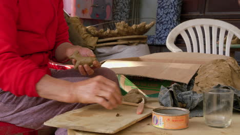 an asian woman crafts animal figures in clay for souvenir flutes, showcasing thanh ha's artistry and cultural heritage